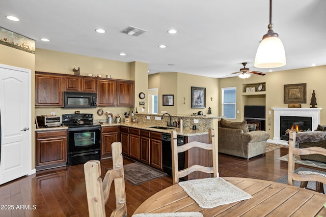 kitchen with visible vents, dark wood-type flooring, black appliances, a sink, and a peninsula