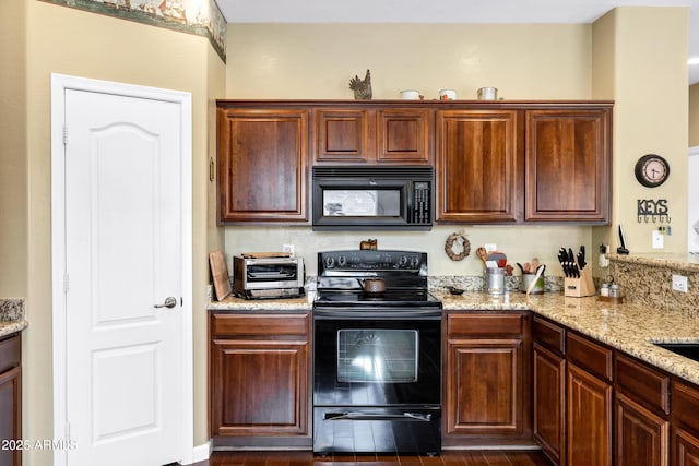 kitchen featuring light stone counters, black appliances, and a toaster