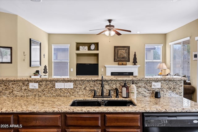 kitchen featuring light stone counters, ceiling fan, a sink, dishwasher, and open floor plan