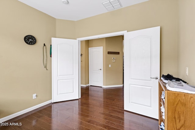 empty room featuring dark wood finished floors, visible vents, and baseboards