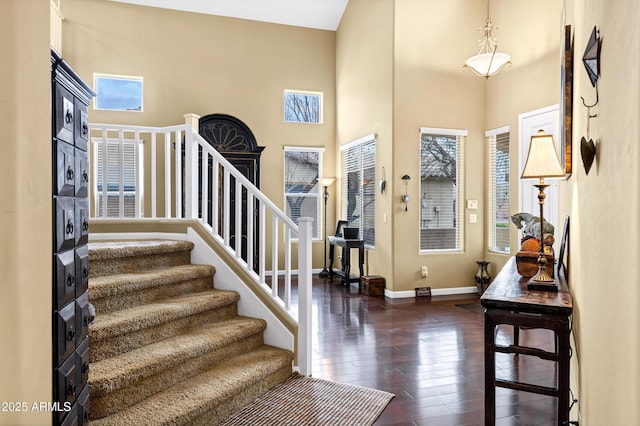 foyer featuring stairway, wood-type flooring, a high ceiling, and baseboards