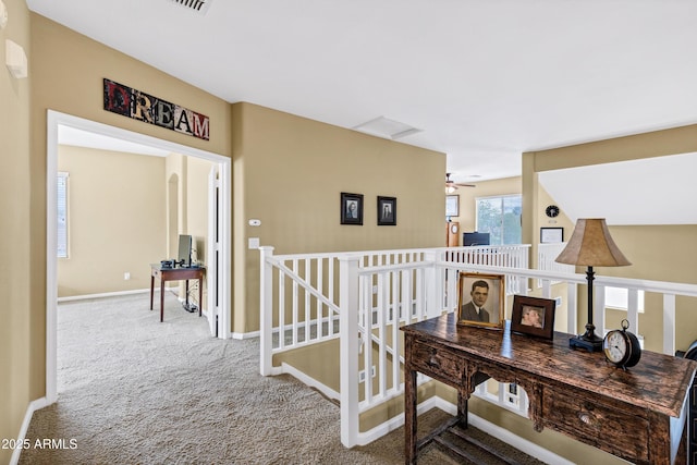 hallway featuring carpet flooring, an upstairs landing, and baseboards