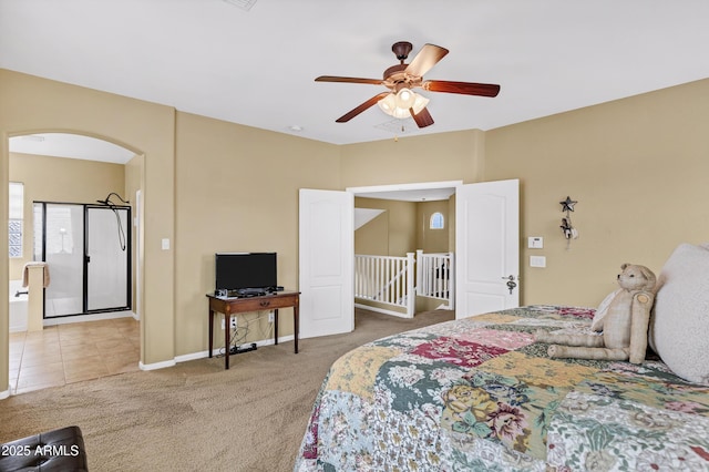 carpeted bedroom featuring baseboards, arched walkways, and ceiling fan