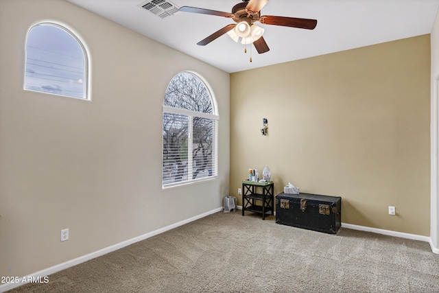 carpeted empty room featuring visible vents, baseboards, and ceiling fan