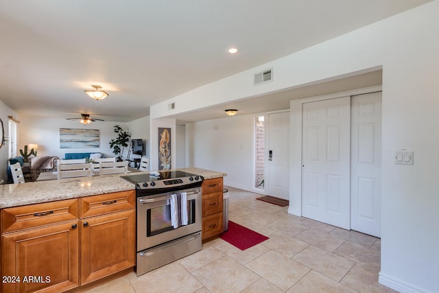 kitchen with stainless steel range with electric cooktop, light tile patterned flooring, light stone counters, and ceiling fan