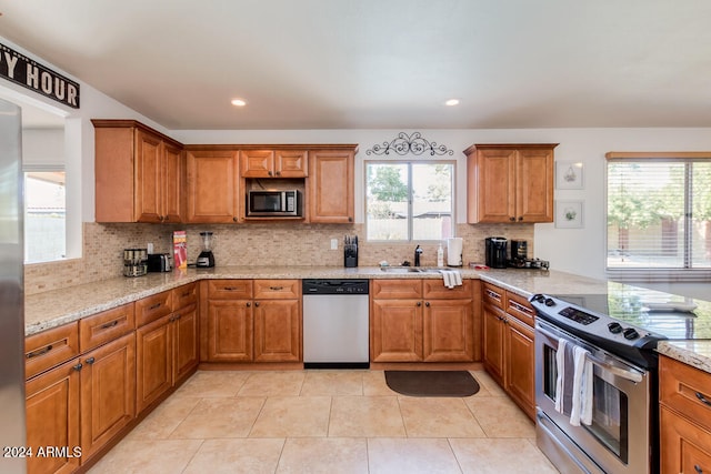 kitchen with light stone counters, sink, decorative backsplash, stainless steel appliances, and light tile patterned floors