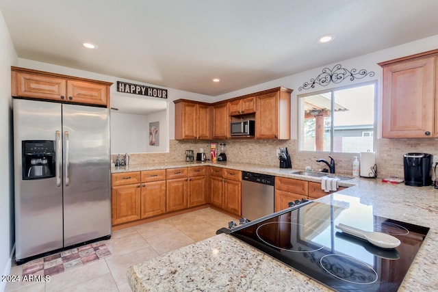 kitchen with light stone counters, light tile patterned floors, sink, appliances with stainless steel finishes, and decorative backsplash