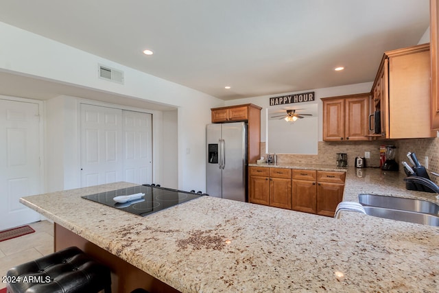 kitchen featuring ceiling fan, kitchen peninsula, tasteful backsplash, appliances with stainless steel finishes, and a kitchen bar