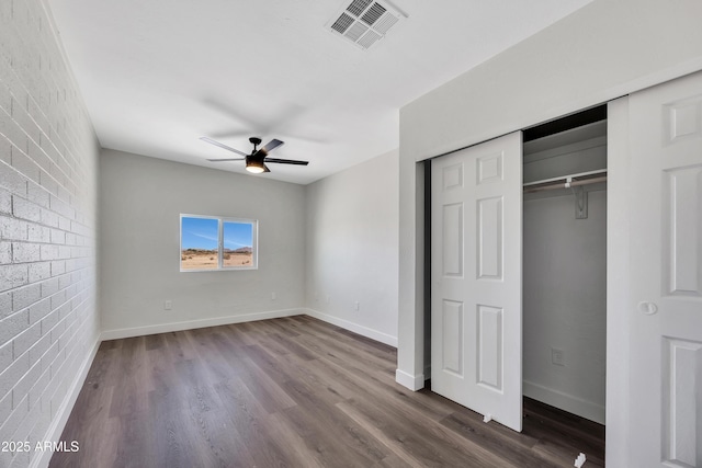 119 W Silver Reef Rd, Casa Grande, AZ 85122 - unfurnished bedroom with brick wall, dark wood finished floors, baseboards, a ceiling fan, and a closet