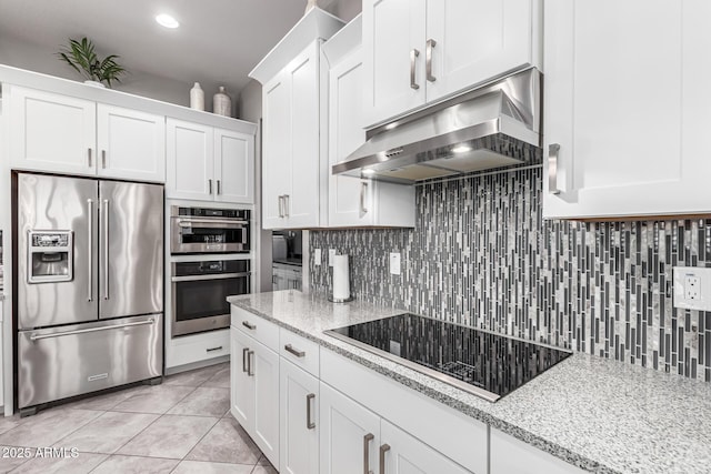 kitchen with light tile patterned floors, stainless steel appliances, under cabinet range hood, decorative backsplash, and white cabinets