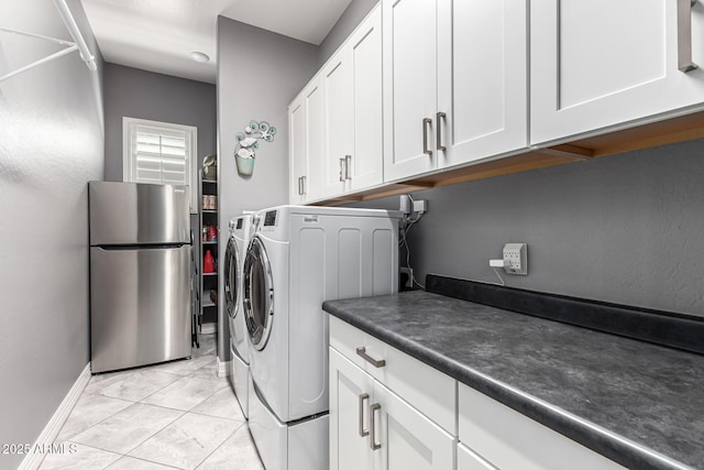 laundry area featuring light tile patterned floors, washer and clothes dryer, cabinet space, and baseboards