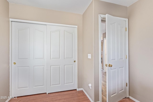 unfurnished bedroom with baseboards, light wood-type flooring, and a closet