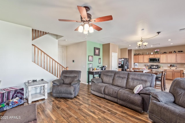 living area featuring ceiling fan with notable chandelier, wood finished floors, recessed lighting, stairway, and baseboards