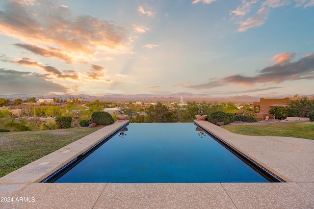 pool at dusk featuring a mountain view