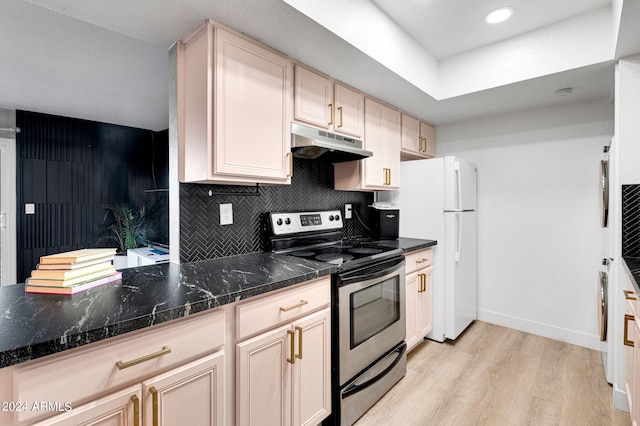 kitchen featuring dark stone counters, light wood-type flooring, electric range, tasteful backsplash, and light brown cabinetry