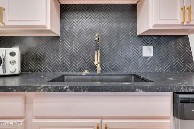 kitchen featuring sink, white cabinetry, and decorative backsplash