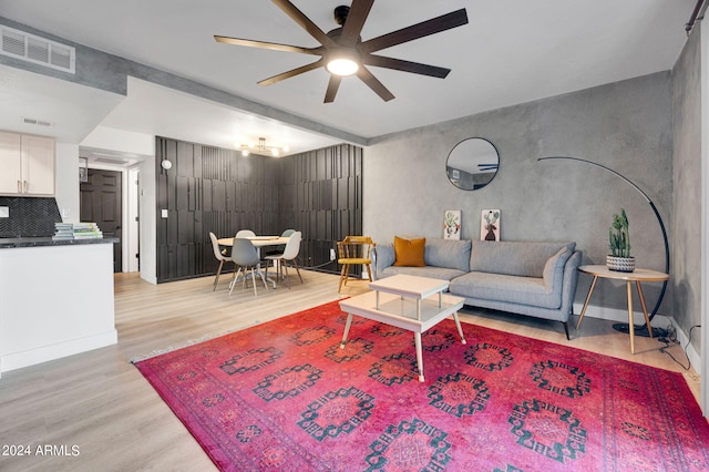 living room featuring ceiling fan, light hardwood / wood-style flooring, and beam ceiling