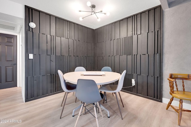 dining area with light wood-type flooring and a notable chandelier