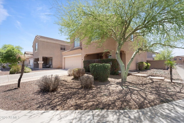 pueblo revival-style home featuring fence, a garage, driveway, and stucco siding