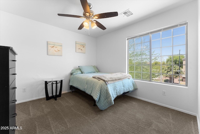 bedroom featuring visible vents, baseboards, dark carpet, and ceiling fan