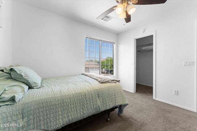 bedroom featuring ceiling fan, visible vents, carpet floors, a walk in closet, and baseboards