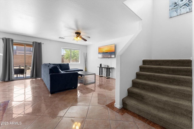 tiled living area with stairs, visible vents, and ceiling fan