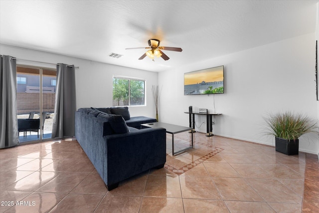 living area featuring light tile patterned flooring, baseboards, a ceiling fan, and visible vents
