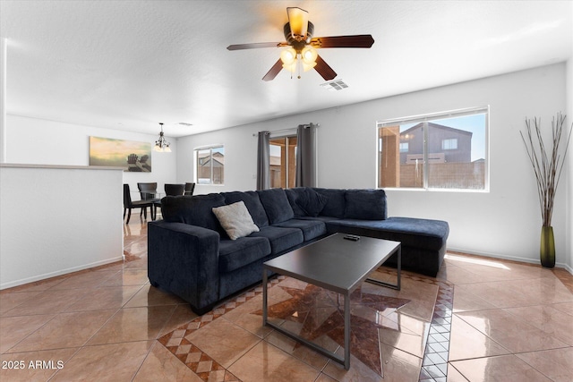 living area with light tile patterned floors, a ceiling fan, visible vents, and a wealth of natural light