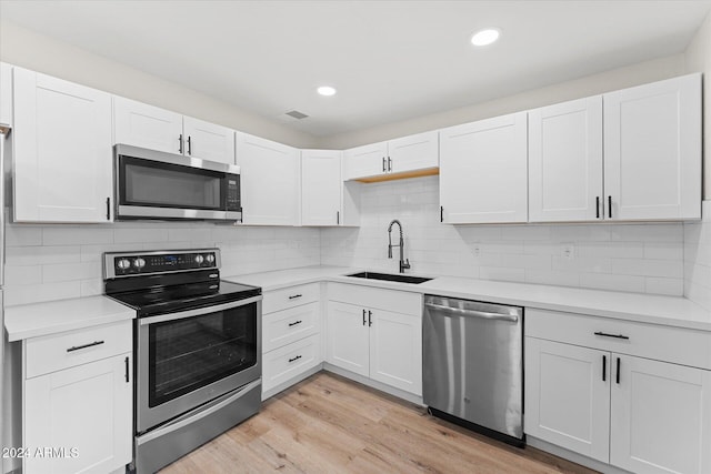 kitchen featuring light wood-type flooring, stainless steel appliances, white cabinetry, and sink