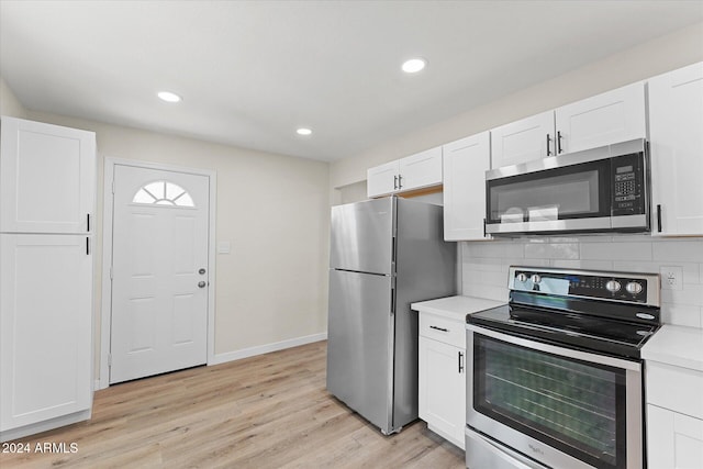 kitchen featuring white cabinets, backsplash, stainless steel appliances, and light hardwood / wood-style flooring