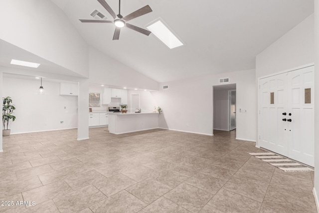 unfurnished living room with a skylight, high vaulted ceiling, and ceiling fan