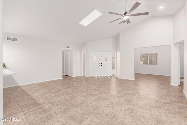 unfurnished living room with a skylight, high vaulted ceiling, and ceiling fan