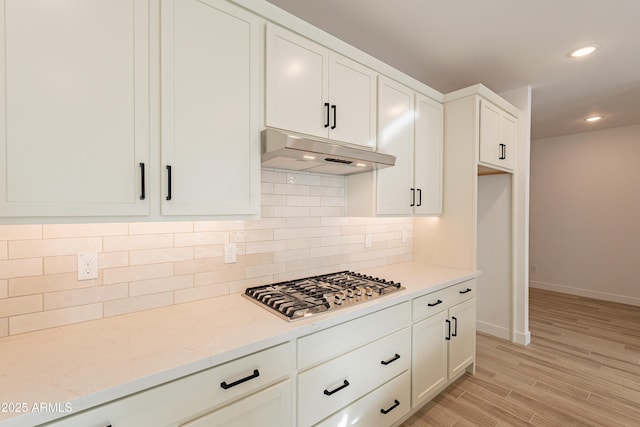 kitchen with white cabinets, light hardwood / wood-style floors, light stone counters, and stainless steel gas cooktop