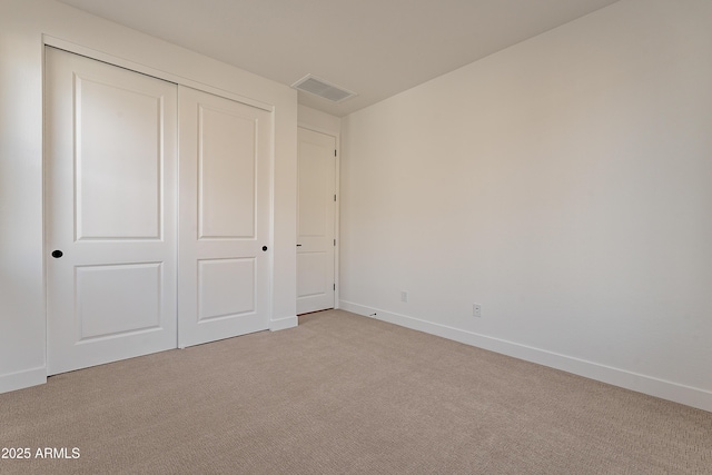 unfurnished bedroom featuring light colored carpet and a closet