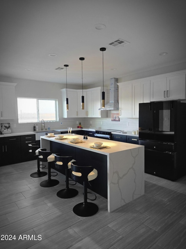 38422 W Buckeye Rd, Tonopah, AZ 85354 - kitchen featuring tasteful backsplash, freestanding refrigerator, a kitchen island, visible vents, and wall chimney exhaust hood