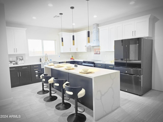 38422 W Buckeye Rd, Tonopah, AZ 85354 - kitchen featuring white cabinetry, a breakfast bar, freestanding refrigerator, a center island, and wall chimney exhaust hood