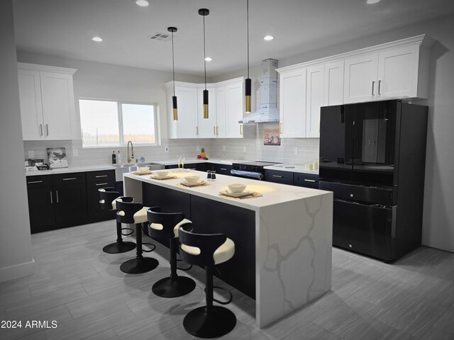 38422 W Buckeye Rd, Tonopah, AZ 85354 - kitchen with a breakfast bar area, dark cabinets, visible vents, freestanding refrigerator, and wall chimney exhaust hood