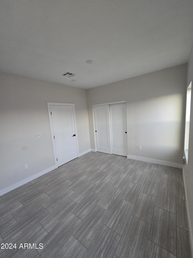 38422 W Buckeye Rd, Tonopah, AZ 85354 - unfurnished bedroom with wood finished floors, visible vents, a closet, and baseboards