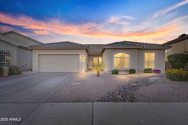 view of front of property with a tiled roof, stucco siding, concrete driveway, and a garage
