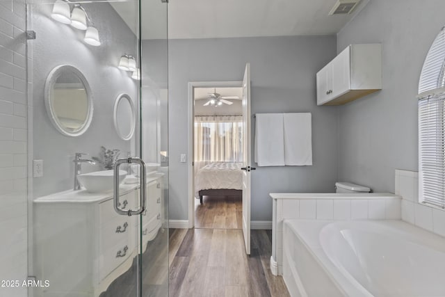 bathroom with visible vents, wood finished floors, baseboards, ceiling fan, and connected bathroom