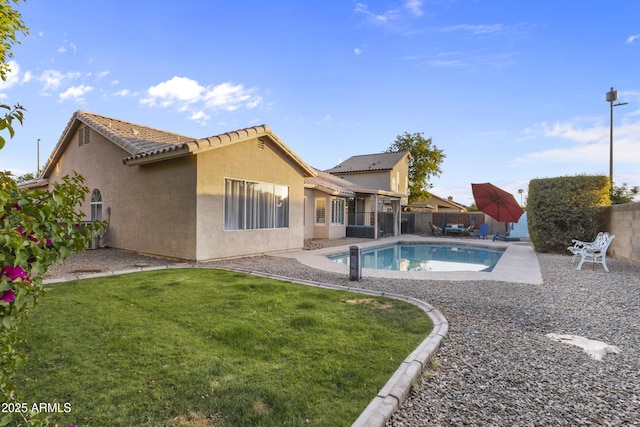 rear view of house with a tiled roof, a fenced in pool, a fenced backyard, and stucco siding