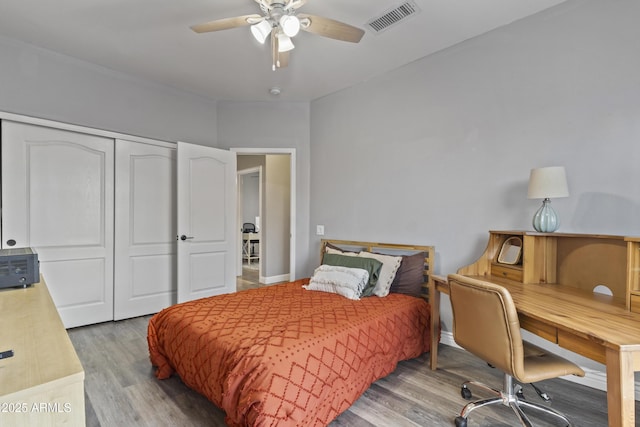 bedroom featuring ceiling fan, visible vents, wood finished floors, and a closet