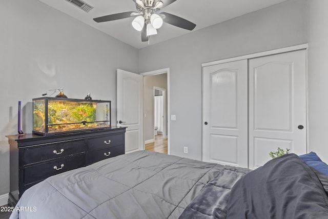 bedroom with visible vents, a closet, wood finished floors, baseboards, and ceiling fan