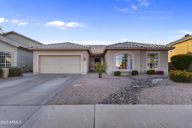 view of front of property featuring an attached garage, stucco siding, concrete driveway, and a tiled roof
