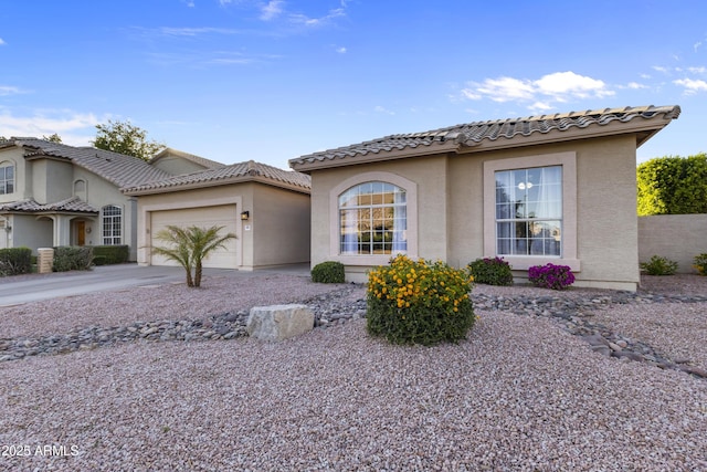 mediterranean / spanish-style home featuring stucco siding, a tiled roof, concrete driveway, and a garage