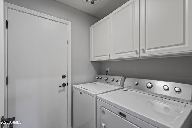 washroom featuring washing machine and dryer, cabinet space, and visible vents