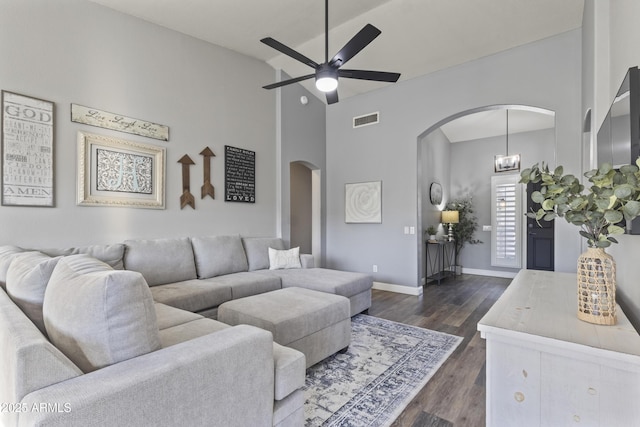 living area featuring ceiling fan, dark wood-style flooring, visible vents, arched walkways, and high vaulted ceiling