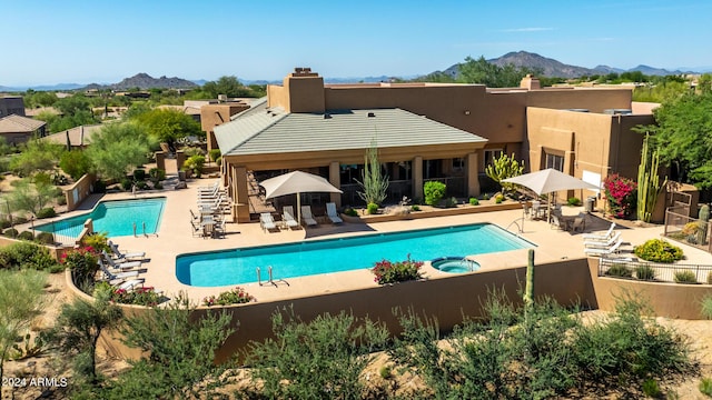 community pool featuring a patio area, a hot tub, fence, and a mountain view