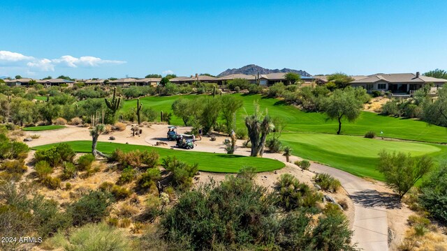 view of property's community featuring view of golf course, a mountain view, and a lawn