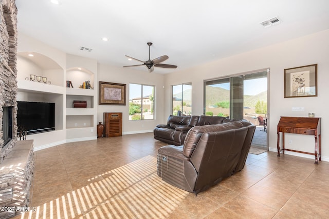 living room featuring light tile patterned floors, ceiling fan, a fireplace, and built in features